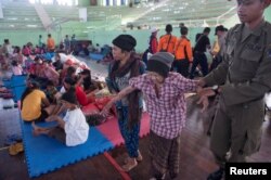 An evacuated villager from locations near the summit of Mount Agung, an active volcano that is showing increased seismic activity, is helped at a temporary shelter in Klungkung, on the resort island of Bali, Indonesia, Sept. 22, 2017.