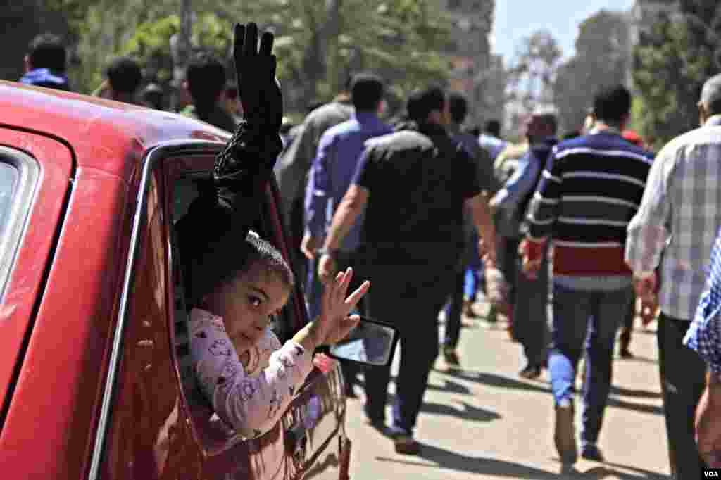 A girl and a woman wave from the window of their car during a protest in Cairo, March 28, 2014. (Hamada Elrassam/VOA)