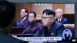 A man at South Korea's Seoul Railway Station views a TV screen showing file footage of North Korean leader Kim Jong Un, in foreground, with education official Kim Yong Jin, second from left.