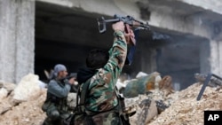 FILE - Syrian soldiers fire their weapons during a battle with rebel fighters at the Ramouseh front line, east of Aleppo, Syria, Dec. 5, 2016.