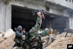 Syrian soldiers fire their weapons during a battle with rebel fighters at the Ramouseh front line, east of Aleppo, Syria, Dec. 5, 2016.