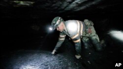 FILE - Coal miner Scott Tiller crawls through an underground coal mine roughly 40 inches high, May 11, 2016, in Welch, W.Va., about 60 miles from a coal mine in Clear Creek where three people missing since the weekend were found alive.