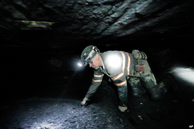 FILE - Coal miner Scott Tiller crawls through an underground coal mine roughly 40 inches high, May 11, 2016, in Welch, W.V. (AP Photo/David Goldman)