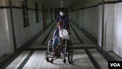 A patient is pushed in a wheelchair along a corridor by a ward boy at Rajiv Gandhi Government General Hospital (RGGGH) in Chennai July 12, 2012. Chennai is the capital of Tamil Nadu, one of two Indian states offering free medicine for all. The state provi