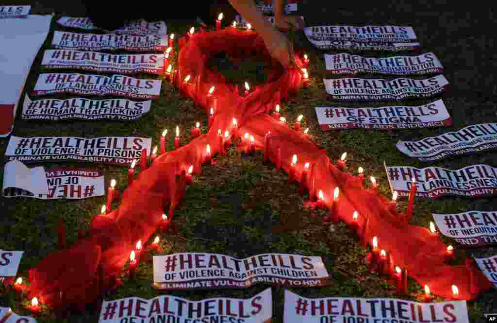 Seorang warga Filipino yang positif HIV menyalakan lilin di sekitar pita merah simbol kesadaran akan penyakit AIDS, dalam acara peringatan Hari AIDS Sedunia di Quezon City, Filipina (1/12). (AP/Aaron Favila)