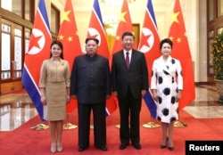 中国国家主席习近平和夫人彭丽媛在北京人大会堂同朝鲜国务委员会委员长金正恩和夫人李雪主合影。（2018年3月28日）