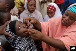 FILE - Health official administers a polio vaccine to a child in Kawo Kano, Nigeria.