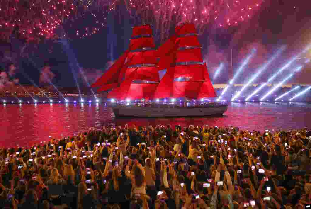 People watch fireworks and a brig with scarlet sails floating on the Neva River during the Scarlet Sails festivities marking school graduation in St. Petersburg, Russia.