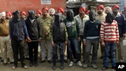Indian policemen stand with six men, face covered in black sheet, suspected in a gang rape of a bus passenger in Punjab state, India, January 13, 2013. 