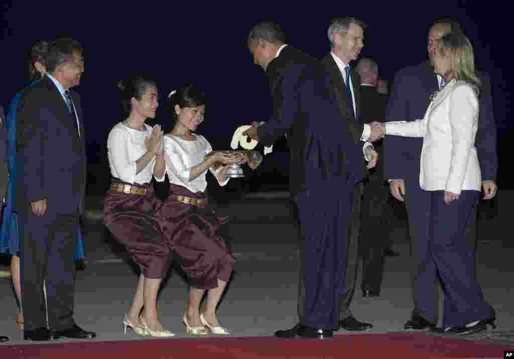 U.S. President Barack Obama is given flowers as he and U.S. Secretary of State Hillary Rodham Clinton, right, arrive at Phnom Penh International Airport in Phnom Penh, Cambodia, on Air Force One, Monday, Nov. 19, 2012, to attend the East Asia Summit. (AP Photo/Carolyn Kaster)