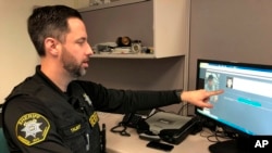In this February 22, 2019, photo, Washington County Sheriff’s Office Deputy Jeff Talbot demonstrates how his agency used facial recognition software to help solve a crime at their headquarters in Hillsboro, Oregon. (AP Photo/Gillian Flaccus)
