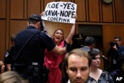 A woman stands and voices her opposition to Supreme Court nominee Brett Kavanaugh, during a Senate Judiciary Committee confirmation hearing on his nomination for Supreme Court, on Capitol Hill, Sept. 4, 2018, in Washington.