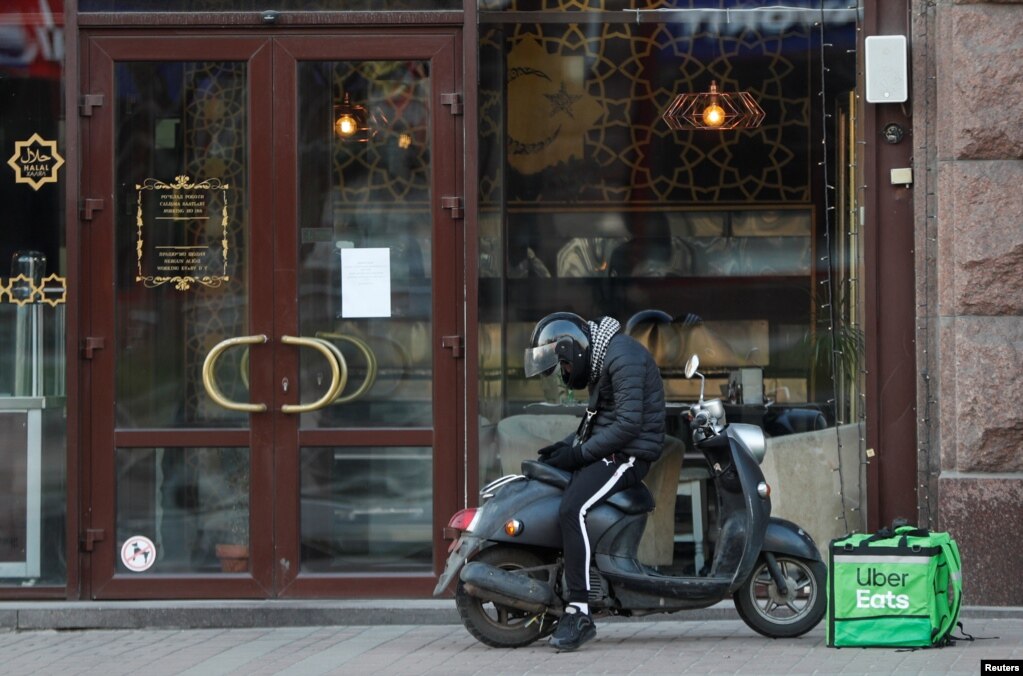 Un mensajero de entrega de alimentos de Uber Eats espera una orden frente a un restaurante, que se cerró como medida para prevenir la propagación de la enfermedad por coronavirus (COVID-19), en el centro de Kiev, Ucrania. Otras ciudades del mundo han adoptado medidas semejantes.&nbsp;