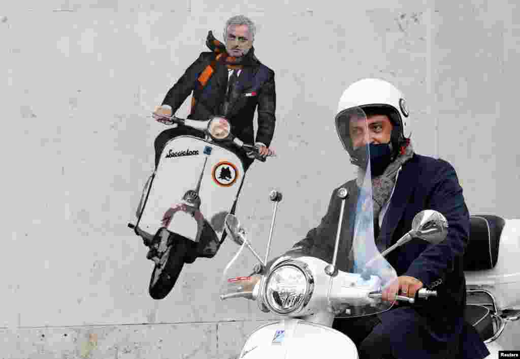 A man drives past a mural depicting new AS Roma coach Jose Mourinho riding a Vespa on a wall in Rome, Italy.