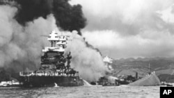 FILE - Part of the hull of the capsized USS Oklahoma is seen at right as the battleship USS West Virginia, center, begins to sink after suffering heavy damage, while the USS Maryland, left, is still afloat in Pearl Harbor, Oahu, Hawaii, Dec. 7, 1941.