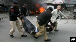Pakistani police officers and a volunteer rush an injured person to a hospital after a bombing in Lahore, Pakistan, Feb. 17, 2015. 