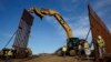 FILE - Construction crews install new border wall sections, Jan. 9, 2019, seen from Tijuana, Mexico. 