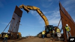 FILE - Construction crews install new border wall sections, Jan. 9, 2019, seen from Tijuana, Mexico. 