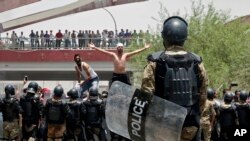 FILE - Iraqi riot police prevent protesters from storming the provincial council building during a demonstration in Basra, 340 miles (550 km) southeast of Baghdad, Iraq, July 15, 2018. 