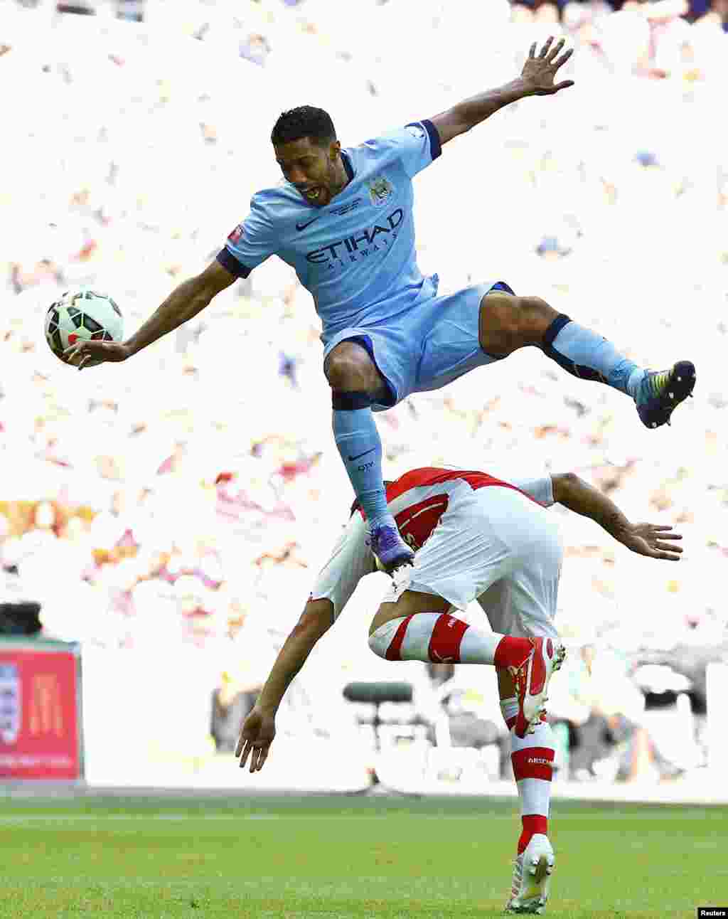 Manchester City&#39;s Gael Clichy (top) leaps above Arsenal&#39;s Santi Cazorla during their English Community Shield soccer match at Wembley Stadium in London.