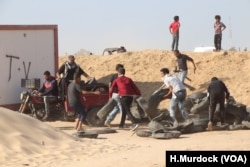 Young men gather tires to burn to hide themselves from Israeli forces on the other side of the border in Gaza, May 15, 2018.