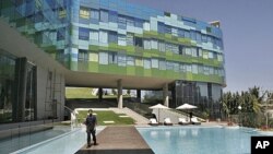 A staff member of Vivanta By Taj, a Tata group hotel, walks past the swimming pool at a newly opened luxury hotel in Bangalore, India, (File January 17, 2009).