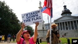 Seorang aktivis mengacungkan tanda yang mendukung penurunan bendera dari ibukota South Carolina (9/7).