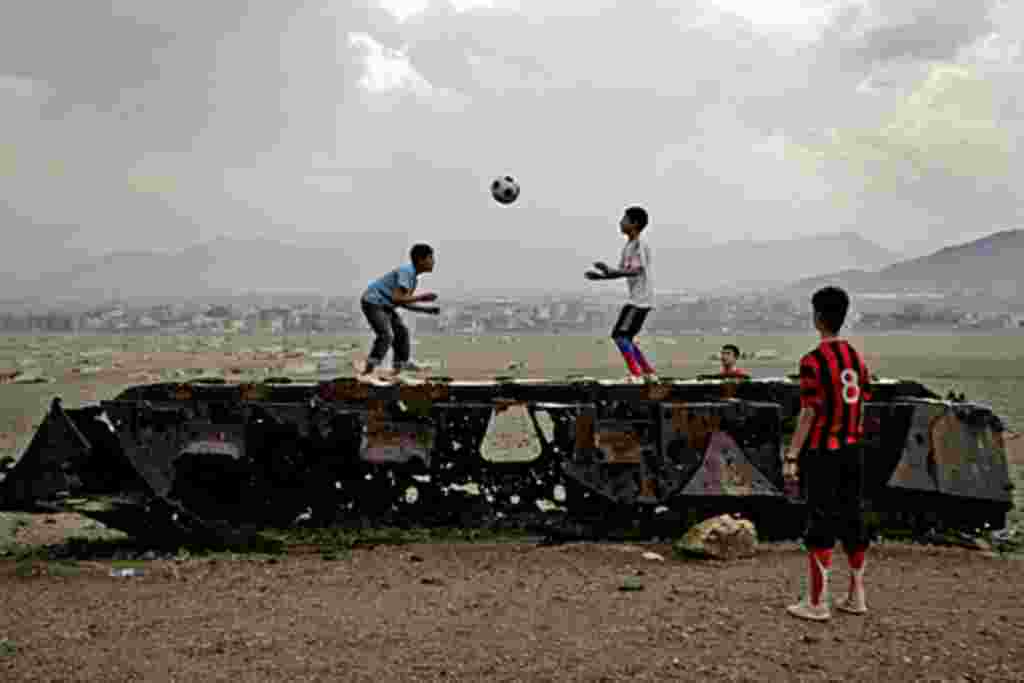 En Kabul, niños afganos juegan a la pelota sobre los restos de un vehículo militar ruso.