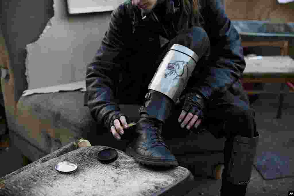 A member of a self-defense volunteer group, with makeshift shin guards bearing a picture of a wolf, polishes his boots in Kyiv&#39;s Independence Square, March 11, 2014.&nbsp;