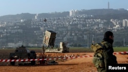 An Israeli soldier stands guard next to an Iron Dome rocket interceptor battery deployed near the northern Israeli city of Haifa, January 28, 2013. 