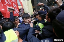 FILE - Hong Kong democracy activist Joshua Wong and others scuffle with police as they protest during the election for Hong Kong's next chief executive near the venue where the vote is taking place in Hong Kong, March 26, 2017.