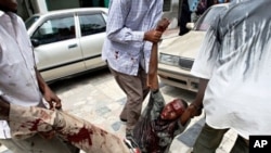 Somali man is carried away from scene of suicide bomb attack during university student graduation ceremony at a local hotel in Mogadishu, 3 Dec 2009