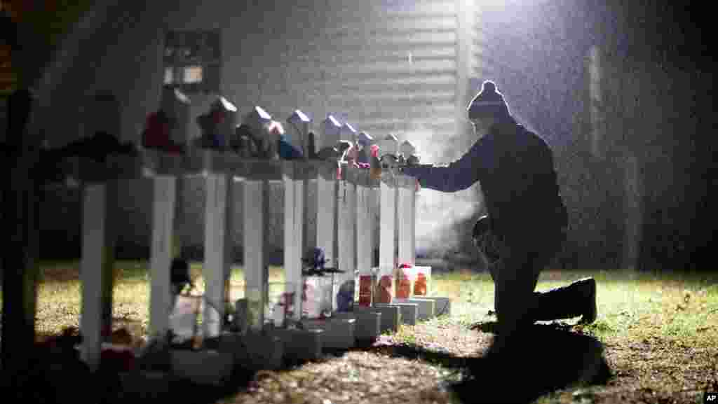 Frank Kulick, adjusts a display of wooden crosses, and a Jewish Star of David, representing the victims of the Sandy Hook Elementary School shooting, on his front lawn in Newtown, Conn., December 17, 2012.