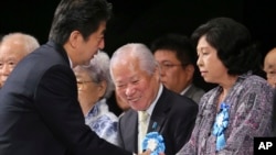 FILE - Japan's Prime Minister Shinzo Abe, left, shakes hands with former abductee Hitomi Soga. (AP Photo/Koji Sasahara)