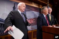 FILE - In this July 27, 2017, photo, Sen. John McCain, R-Ariz., left, jokes around as he and Lindsey Graham, R-S.C., center, and Sen. Ron Johnson, R-Wis., speak to reporters at the Capitol in Washington.