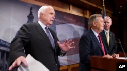 FILE - In this July 27, 2017, photo, Sen. John McCain, R-Ariz., left, jokes around as he and Lindsey Graham, R-S.C., center, and Sen. Ron Johnson, R-Wis., speak to reporters at the Capitol in Washington.