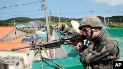 South Korean army soldiers aim their machine guns as they search for a conscript soldier who is on the run after a shooting incident in Goseong, June 22, 2014. 