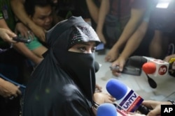 FILE - Karen Aizha Hamidon, who allegedly worked to encourage several Indian militants last year to join the Islamic State group in the Middle East, is surrounded by reporters after attending a hearing at the Department of Justice in Manila, Philippines, Nov. 3, 2017.