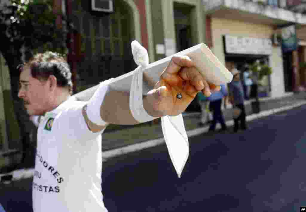 Roberto Gonzalez, dengan membawa kayu salib, mengikuti unjuk rasa menuntut kompensasi terhadap perusahaan pembangun bendungan di Asuncion, Paraguay.