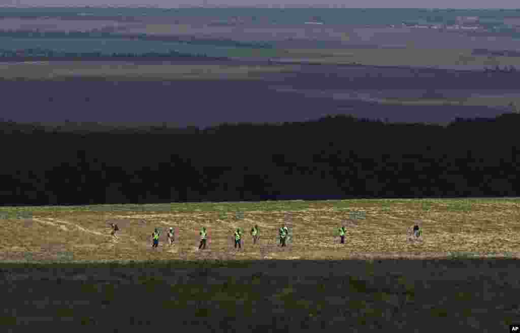 Australian and Dutch experts examine an area at the scene of the downed Malaysia Airlines Flight 17 plane near the village of Rossipne, Donetsk region, eastern Ukraine, Aug. 3, 2014.