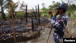 FILE - A Myanmar border guard police officer takes pictures of the remains of a burned down house in Tin May village, northern Rakhine state, Myanmar, July 13, 2017.