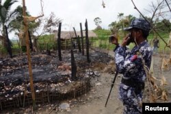 FILE - A Myanmar border guard police officer takes pictures of the charred remains of a house in Tin May village, northern Rakhine state, Myanmar, July 13, 2017. A U.N. fact-finding mission has called for a genocidal probe into several of Myanmar's top military commanders following its campaign in northern Rakhine State last year, which saw an estimated 700,000 mainly Rohingya flee into Bangladesh.