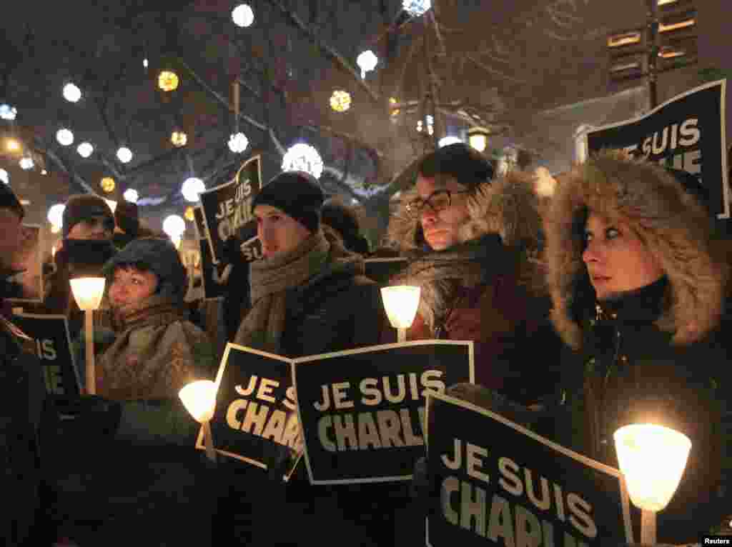 People participate in a vigil to pay tribute to the victims of a shooting, by gunmen at the offices of weekly satirical magazine Charlie Hebdo in Paris, in front of City Hall in downtown Montreal, Jan. 7, 2015.