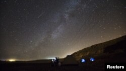 FILE - A meteor streaks across the sky in the early morning as people watching during the Perseid meteor shower in Ramon Carter near the town of Mitzpe Ramon, southern Israel, August 13, 2015. The Perseid meteor shower is sparked every August when the Earth passes through a stream of space debris left by comet Swift-Tuttle.
