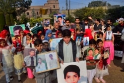 Pakistani families hold portraits of their loved ones, who were killed in a 2014 assault by Pakistani Taliban militants on an army public school that killed 150 people, during a ceremony honoring them, in Peshawar, Pakistan, Dec. 14, 2021.