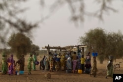 FILE - Women crowd a well in the village of Kiral, near Goudoude Diobe in the Matam region of northeastern Senegal.