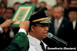 Seorang lelaki memegang Alquran ketika Gubernur Jakarta Anies Baswedan berdiri saat upacara pelantikan di Istana Presiden di Jakarta, 16 Oktober 2017. (Foto: Reuters/Beawiharta)