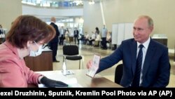 Ruski predsednik pokazuje svoj pasoš članovima izborne komisije pre glasanja (Foto: AP)