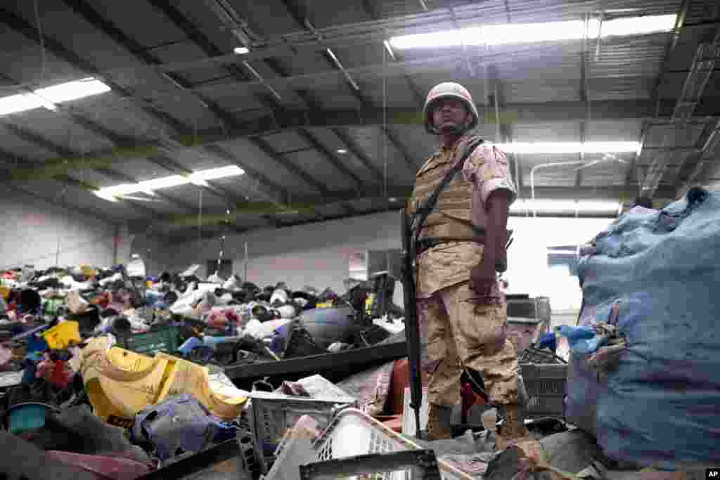 Un soldado mexicano monta guardia entre deshechos para reciclaje en un negocio donde fue encontrada la entrada al t&uacute;nel.