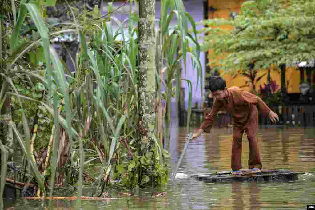 A boy travels through floodwaters in an improvised raft he made in Jal Besar, Malaysia&#39;s northeastern town of Tumpat, which borders with Thailand. Serious flooding for almost a week is showing some respite but has damaged homes, caused loss of income and disrupted schooling.